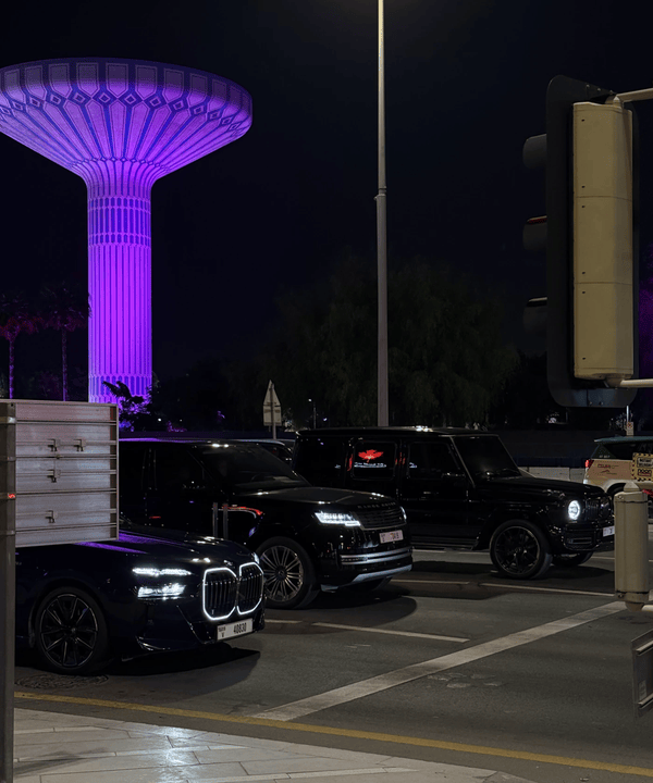 Cars at a Dubai junction at night under a purple-lit water tower